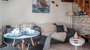 A dining area with a table set for four, a sofa, and a staircase. - Kyriaki' s Cozy Appartment (Chania)