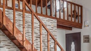 A wooden staircase with a stone wall, a wooden ceiling, and a door with a glass panel. - Kyriaki' s Cozy Appartment (Chania)
