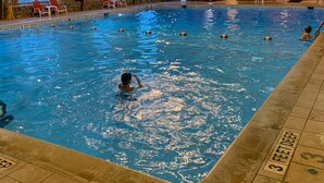 Una piscina interior con múltiples carriles, paredes de madera y un techo con luces colgantes.