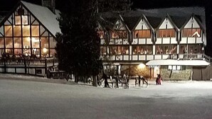 Un edificio grande de varios pisos con amplias ventanas y suelo cubierto de nieve.