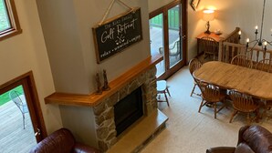 Una sala de estar acogedora con chimenea de piedra, sofás de cuero y un comedor con mesa y sillas de madera.