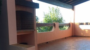 A covered patio with a brick floor, a brick fireplace, and a view of greenery. - T4 plus T2 independent. (Pietrosella)