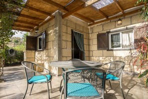 A covered patio with a round table and four chairs, stone walls, and a wooden ceiling. - Secluded Casita in Sunny Southeast with Private Pool, Terrace and Barb (Candelaria)