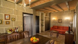 Un intérieur rustique avec une table à manger en bois, un canapé rouge, des murs en pierre et un lustre.