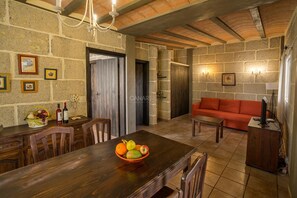 A rustic interior with a wooden dining table, a red sofa, stone walls, and a chandelier. - Secluded Casita in Sunny Southeast with Private Pool, Terrace and Barb (Candelaria)