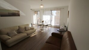 A living room with a sofa, a coffee table, and a dining area with chairs and a table. - Le Renoir (Nice)