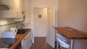 A compact kitchen with white cabinets, a microwave, a toaster, and a sink. - Le Renoir (Nice)