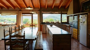 A kitchen with a large island, wooden ceiling beams, and a view of the mountains.