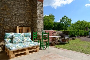 Un'area salotto esterna rustica con un divano in pallet di legno, sedie verdi e un tavolino.