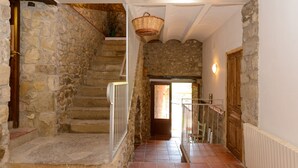 A stone staircase leading to a wooden door, with a basket hanging from the ceiling and a radiator on the wall.