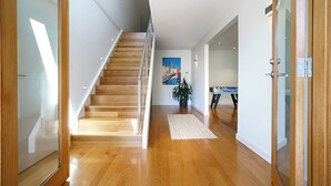 Ein modernes Interieur mit einer Holztreppe, einem Gemälde an der Wand und einer Pflanze.