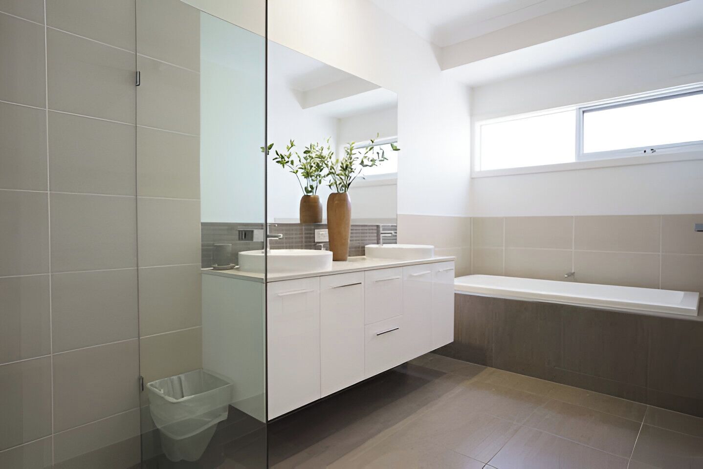 Une salle de bain moderne dotée d’une douche à parois de verre, d’un grand meuble-lavabo et d’une baignoire.