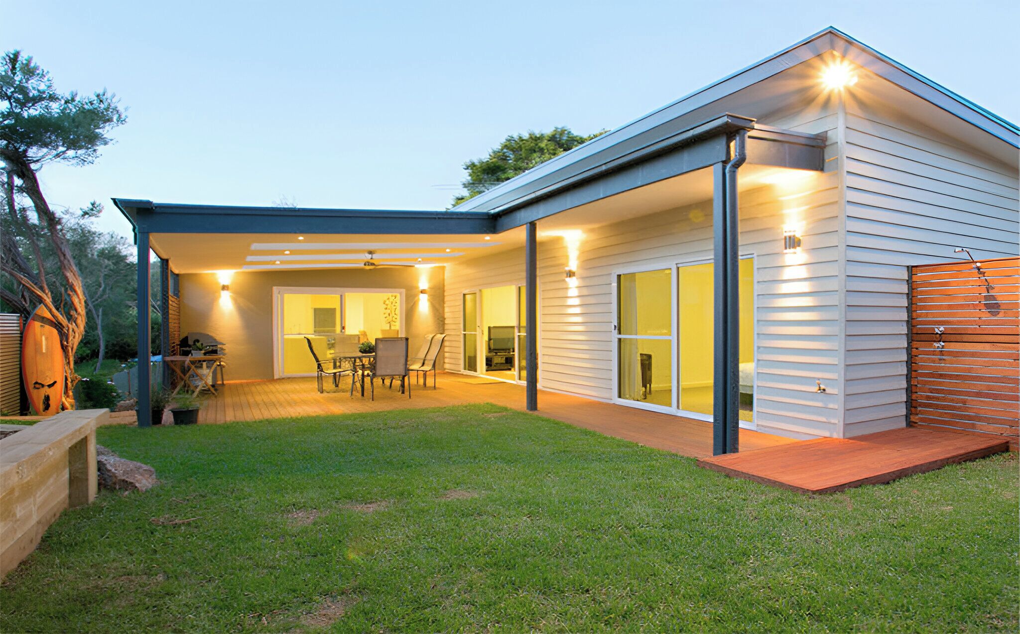 A modern house with a covered patio, a dining area, and a large sliding glass door leading to a living room.