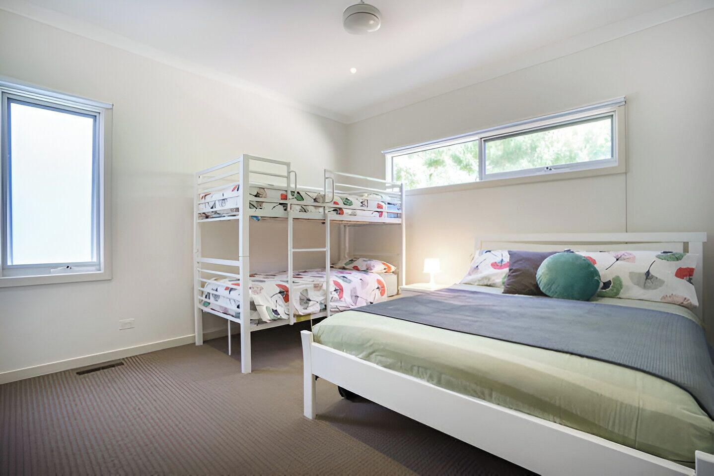 A bedroom with bunk beds, a single bed, a window, and a ceiling light.