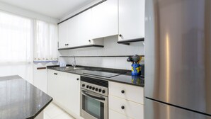 A modern kitchen with white cabinets, a stainless steel refrigerator, and a black countertop. - BEGONIA - Apartment with sea views in Daimuz. Free WiFi (Daimús)