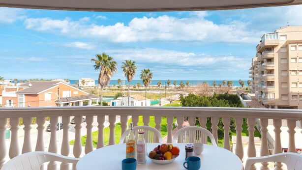 A balcony with a table set for two, a bowl of fruit, and a bottle of water. - BEGONIA - Apartment with sea views in Daimuz. Free WiFi (Daimús)