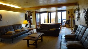 Un vaste salon doté d’un plafond en bois, d’un canapé, d’une table basse et d’un coin repas avec une table et des chaises.