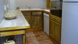 Une cuisine compacte avec des meubles en bois, un réfrigérateur blanc, un four encastré et un pare-feu en carreaux.