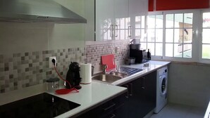 Une cuisine moderne équipée d’un évier en acier inoxydable, d’une machine à café et d’un lave-linge.