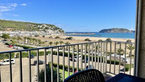 Un balcón con vista a una playa, un estacionamiento y un pueblo lejano.
