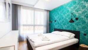 A modern hotel room with a large bed, a desk, and a window with curtains. - Modern Apartment | Parking, Balcony with View (Gdansk)