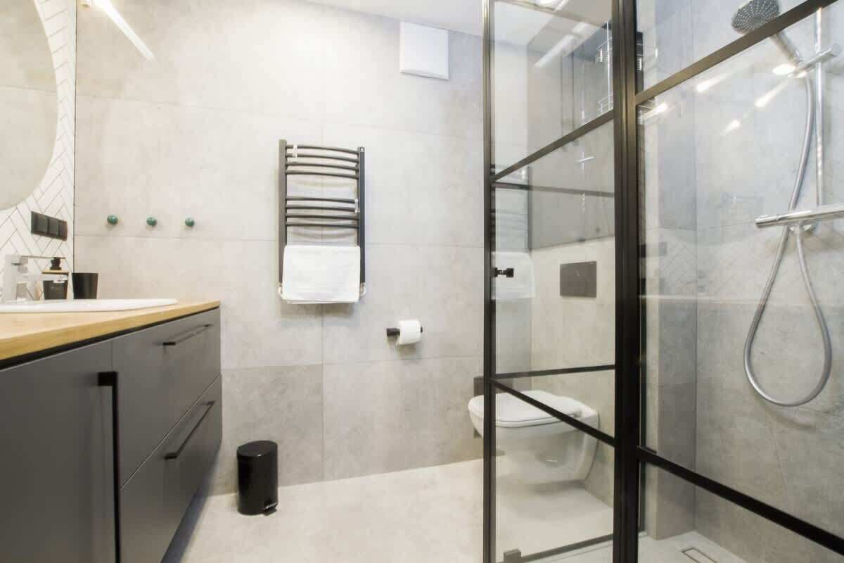 A modern bathroom with a glass shower enclosure, a toilet, and a towel rack.