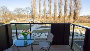 A balcony with a table and chairs, a vase of flowers, and a view of leafless trees and a snow-covered landscape. - Modern Apartment | Parking, Balcony with View (Gdansk)