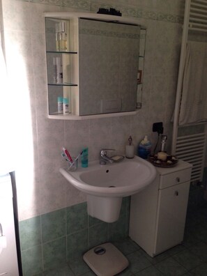 Casa de banho com lavatório, espelho e produtos de higiene.