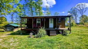 A wooden cabin with a porch, a small shed, and a birdcage. - Gnome away from home (Sweetwater)