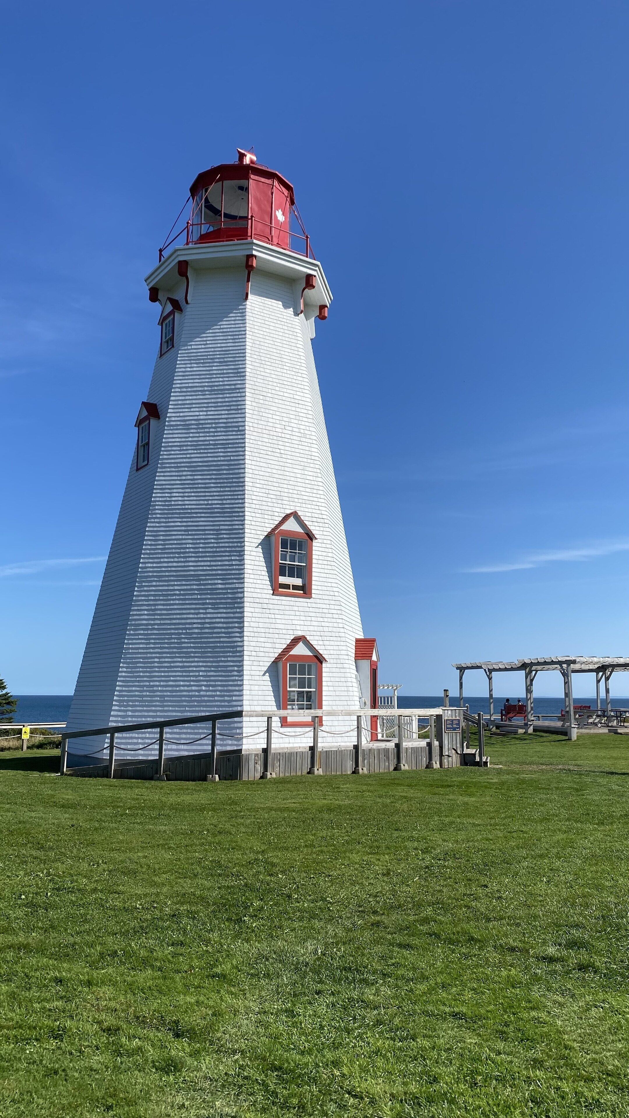 Un faro con exterior blanco y rojo, una ventana pequeña y un tejado rojo.