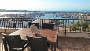 A terrace with a view of a marina, featuring a table and chairs, and a decorative fish sculpture. - Apartaments  Nàutic Xaloc first line of the sea (Escala, L')