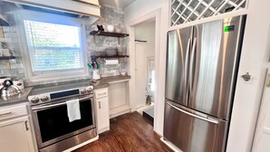 A modern kitchen with stainless steel appliances, a wooden floor, and a window providing natural light.