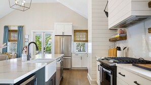Une cuisine moderne avec des meubles blancs, des appareils en acier inoxydable et un plancher en bois.
