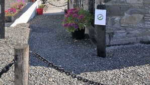 A stone building with a sloped roof, a gravel pathway, and potted plants.