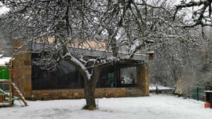 A stone building with a large window and a tree in front.