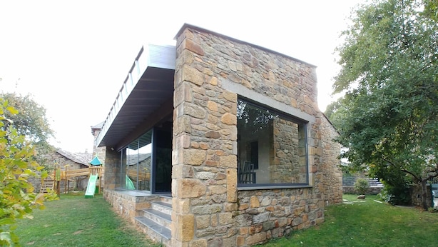 A stone house with a large window and a wooden deck.