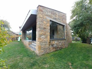 Ein Steinhaus mit einem großen Fenster und einer Holzterrasse.