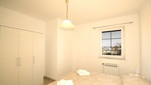 A bedroom with a bed, a window, a radiator, and a wardrobe. - Comfortable and charming apartment, beside the nature park (Premantura)