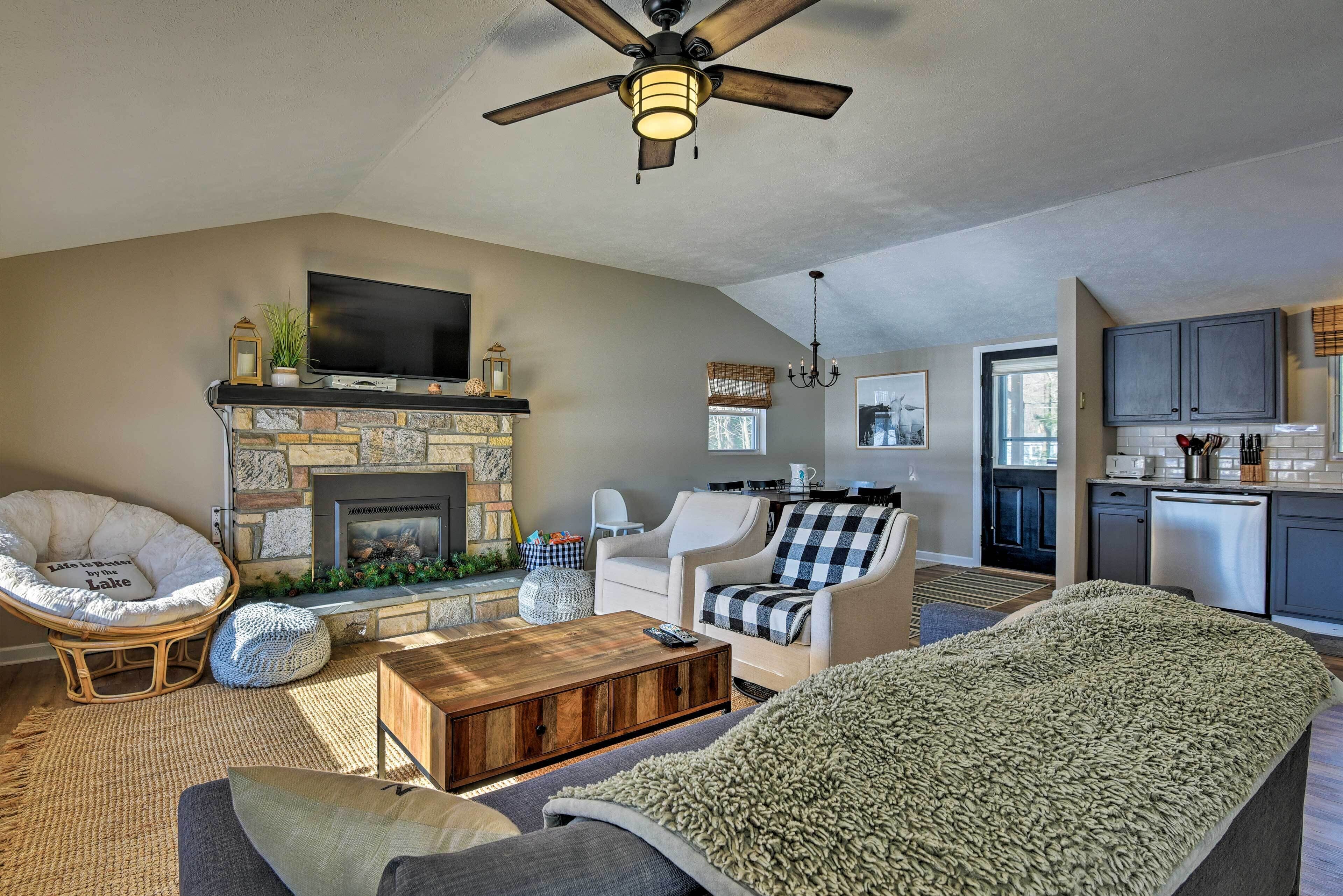 A spacious living room with a fireplace, comfortable seating, and a kitchen area visible through an open doorway.