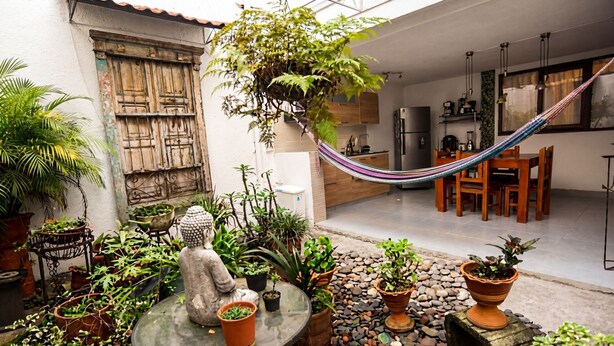 A courtyard with potted plants, a hammock, and a statue. - Alameda House   a beautiful apartment located in Medellín (Medellín)
