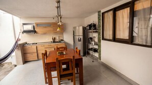 A compact kitchen with wooden cabinets, a stainless steel refrigerator, a built-in oven, and a dining table with chairs. - Alameda House   a beautiful apartment located in Medellín (Medellín)