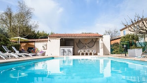 Une piscine avec des chaises longues et un espace salon abrité.