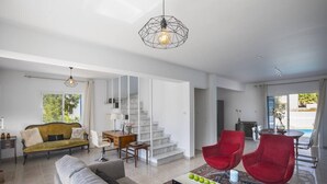 A spacious living room with a sofa, red chairs, a coffee table, and a staircase leading to another level.
