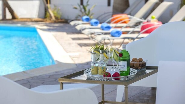A poolside area with lounge chairs, a tray table with drinks and snacks, and a clear view of the pool.