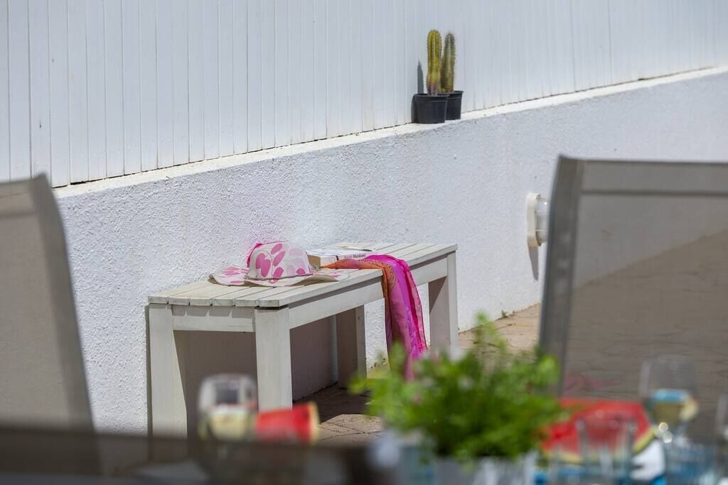Un petit espace extérieur aménagé avec un banc, une table et un pot de fleurs.