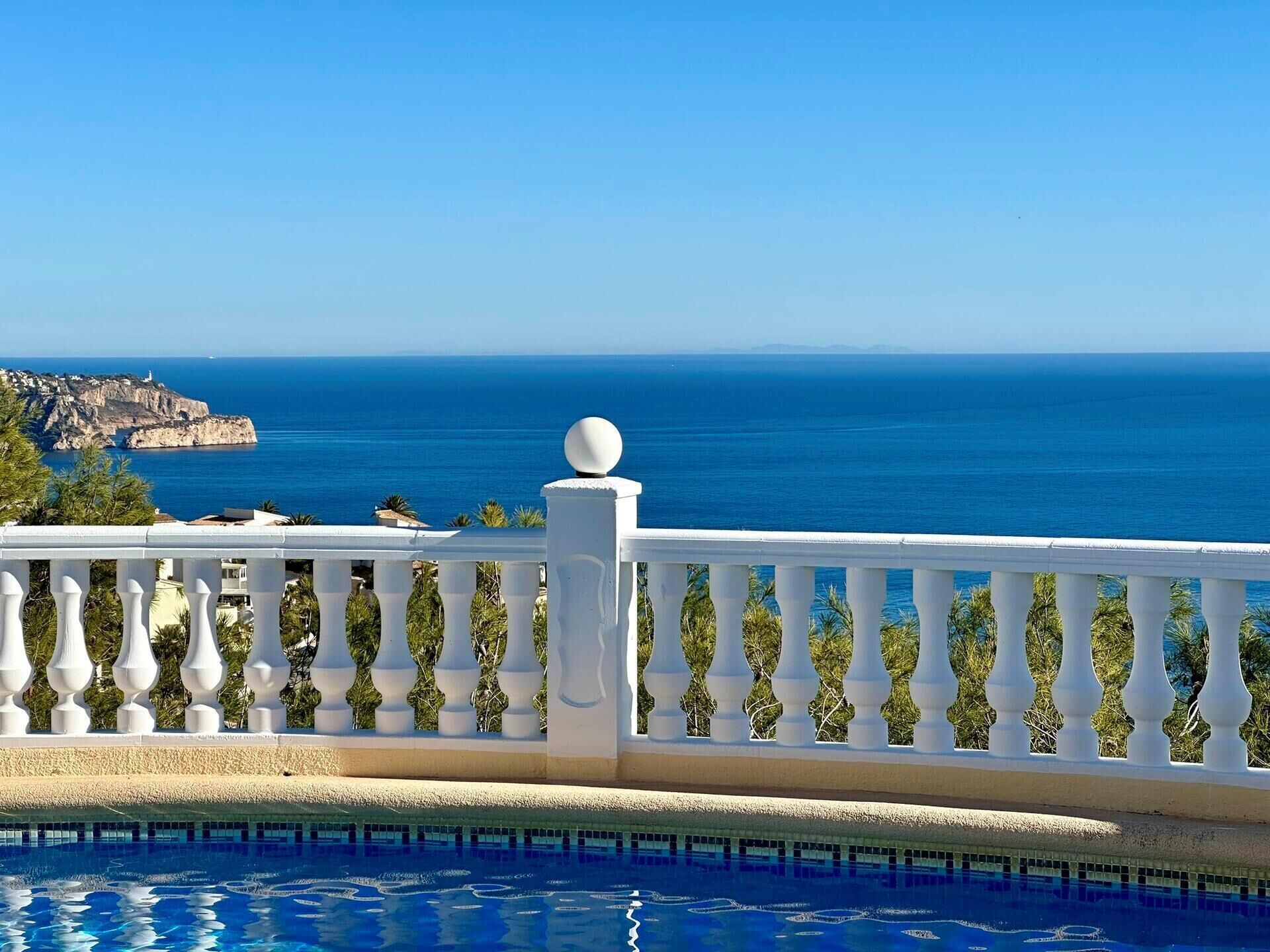Ein Pool mit weißem Geländer und Blick aufs Meer.