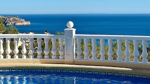 Una piscina con ringhiera bianca e vista sul mare.