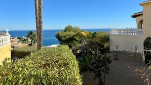 Una proprietà vista mare, con palme e un giardino.
