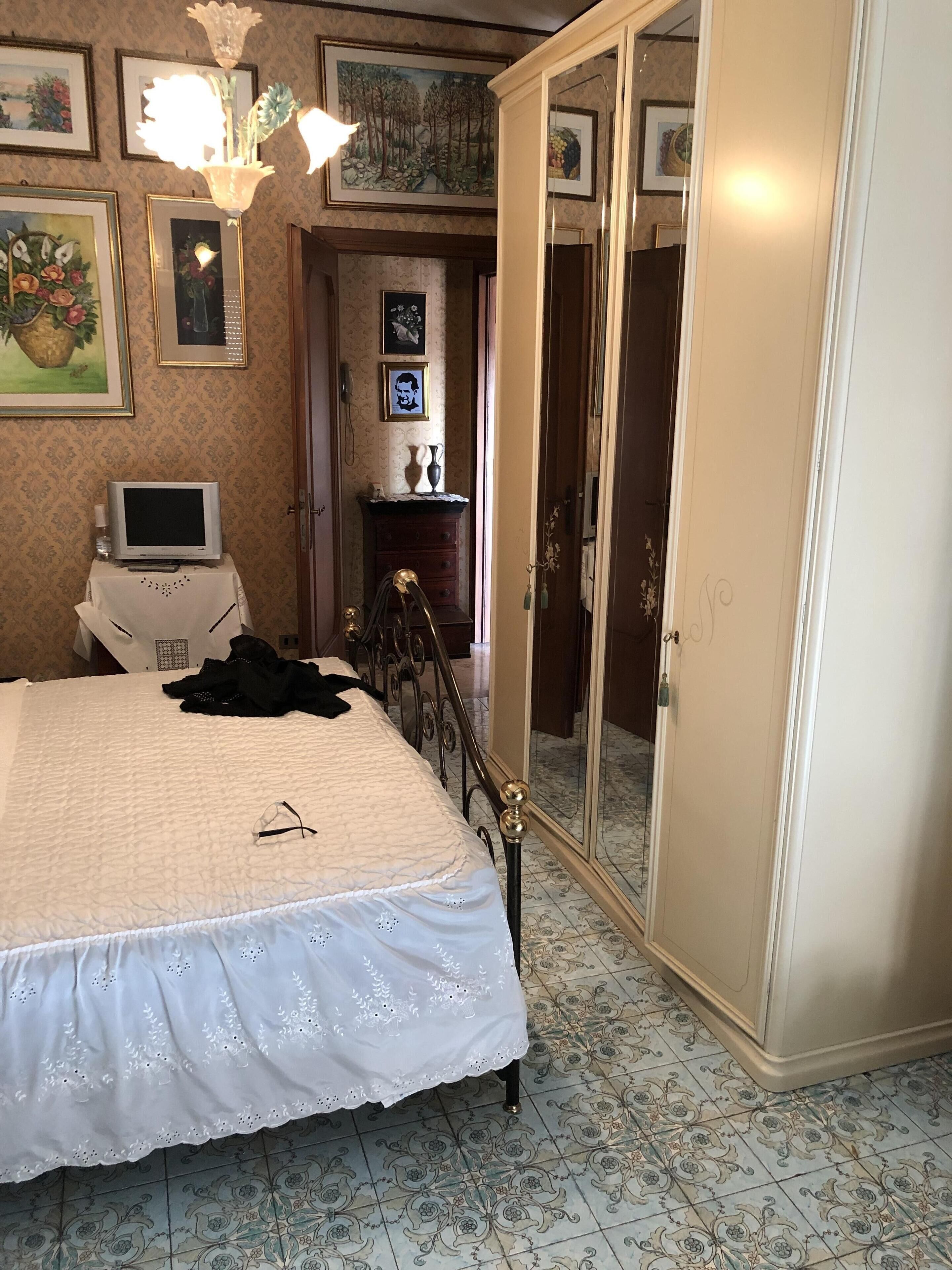 Une chambre à coucher avec un lit, une commode, un téléviseur et une armoire.