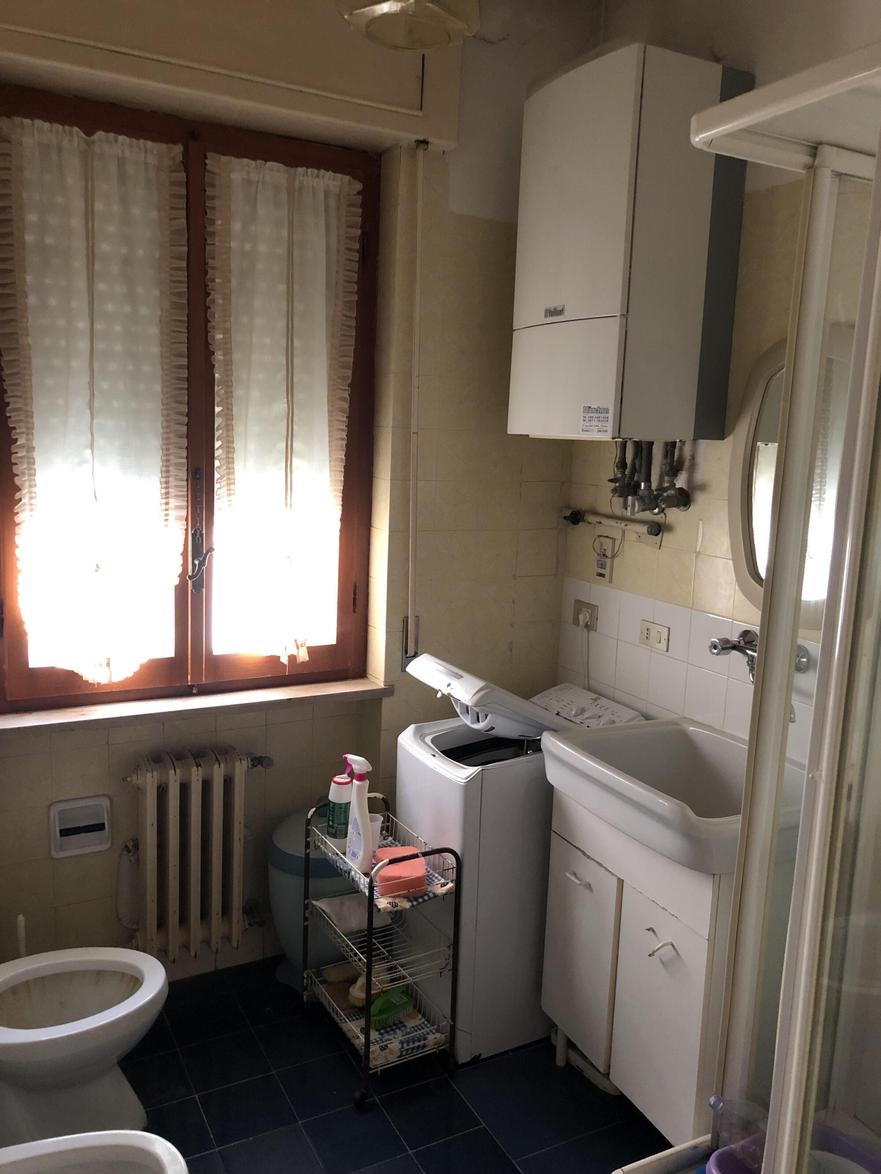 Een kleine badkamer met toilet, een wasmachine en een wastafel.